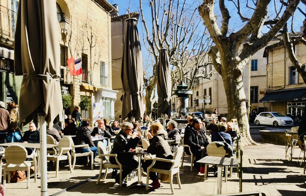 French café terrace with people enjoying coffee and wine, illustrating lifestyle beyond the cost of living in France.