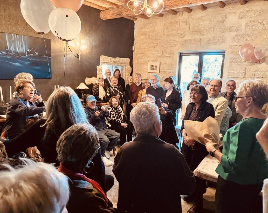 Friends gathered indoors celebrating an 80th birthday in Uzès France